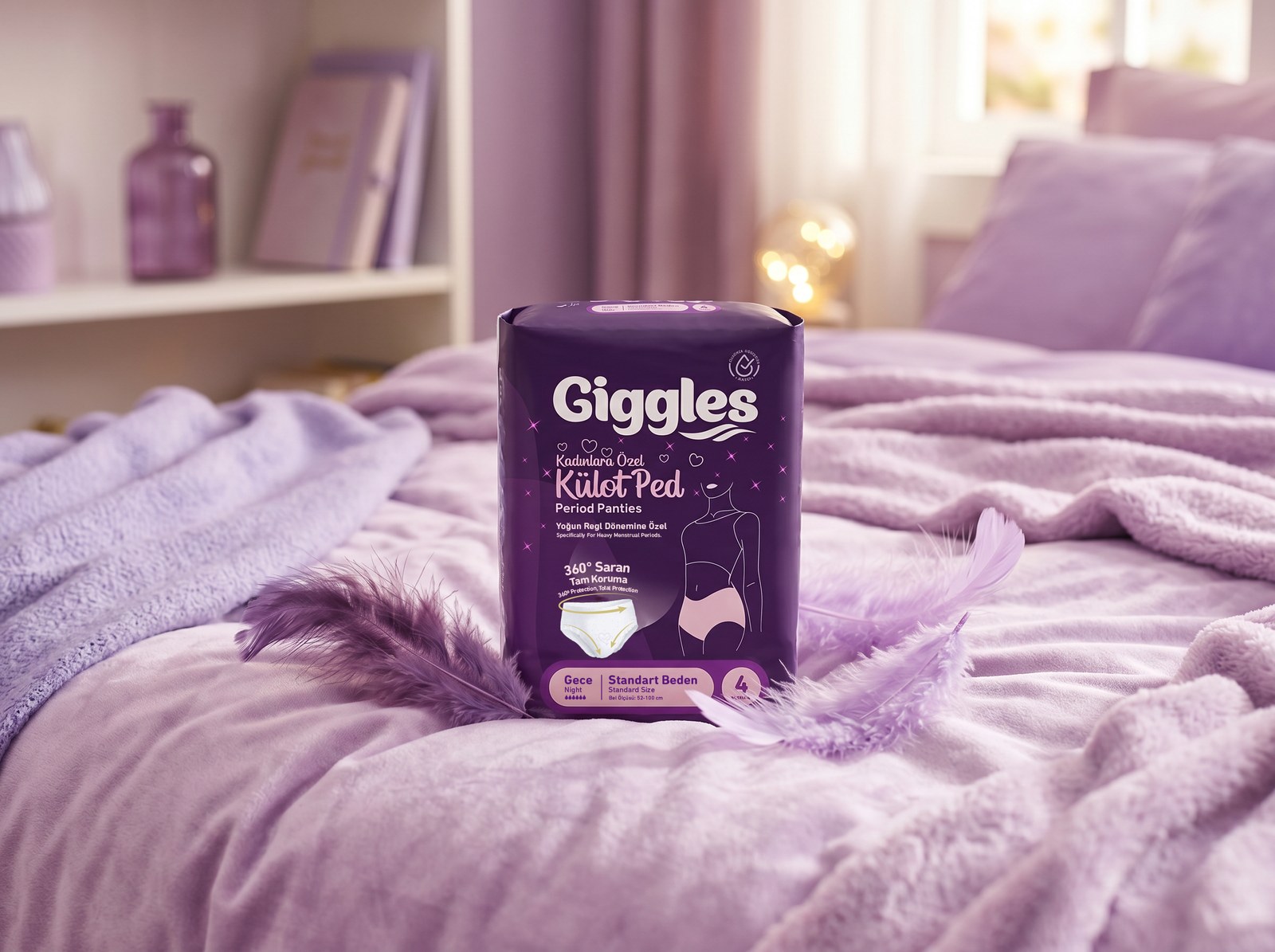 Lila bir yatak örtüsünün üzerinde duran Giggles Külot Ped paketi